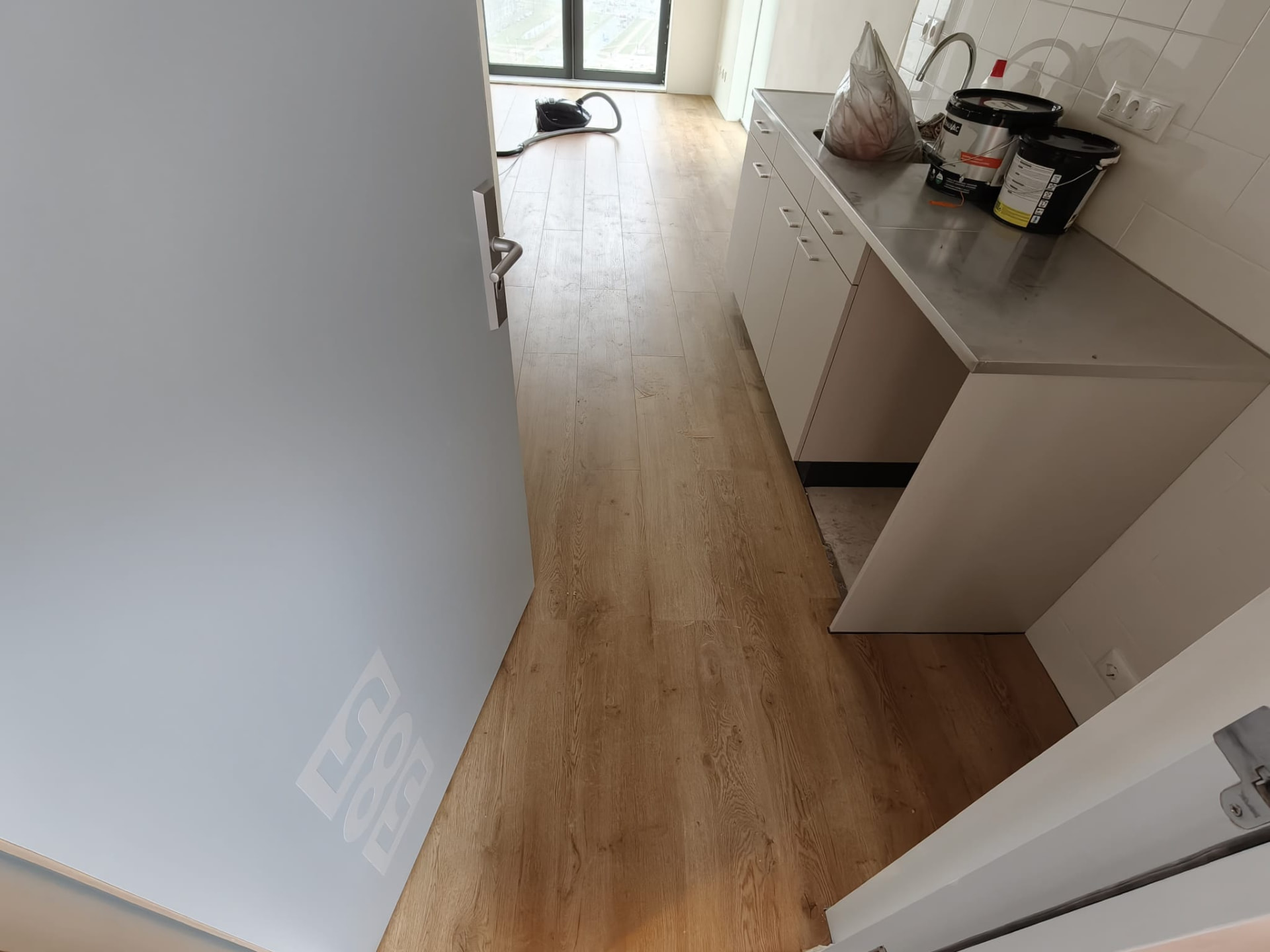 Nieuw gelegde houtlook vloer met keuken tijdens oplevering