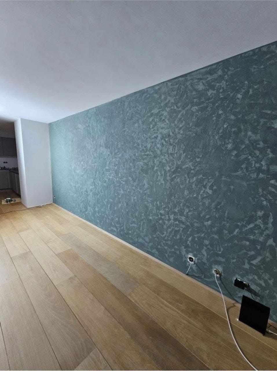 Woonkamerwand met decoratief stucwerk in petrolblauw